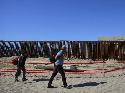 Migrants walk near the border fence, at Playas de Tijuana, in Tijuana, Mexico October 2, 2023. REUTERS/Jorge Duenes