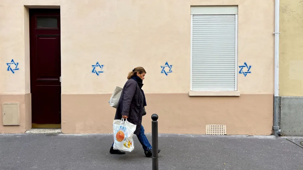 A woman walks past a building tagged with Stars of David in Paris, France, October 31, 2023. REUTERS/Lucien Libert