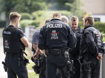 Police officers coordinate the search for a wild animal in a residential area in Teltow, Germany, Thursday July 20, 2023. German authorities warned people in Berlin's southern suburbs on Thursday to watch out for a potentially dangerous animal, suspected to be a lioness, that was on the loose. (Fabian Sommer/dpa via AP)