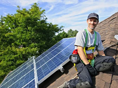 Man installing alternative energy photovoltaic solar panels on roof