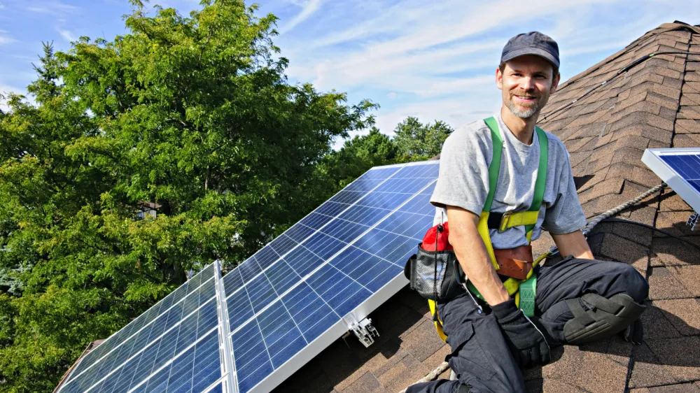 Man installing alternative energy photovoltaic solar panels on roof