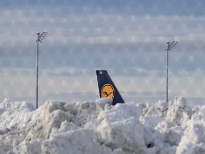 A tail fin of a Lufthansa plane is pictures behind snow at the terminal as Munich Airport has cancelled all incoming and outgoing flights until 12 p.m. (1100GMT) due to a forecast for sleet in Munich, Germany, December 5, 2023. Picture taken through a fence.   REUTERS/Angelika Warmuth