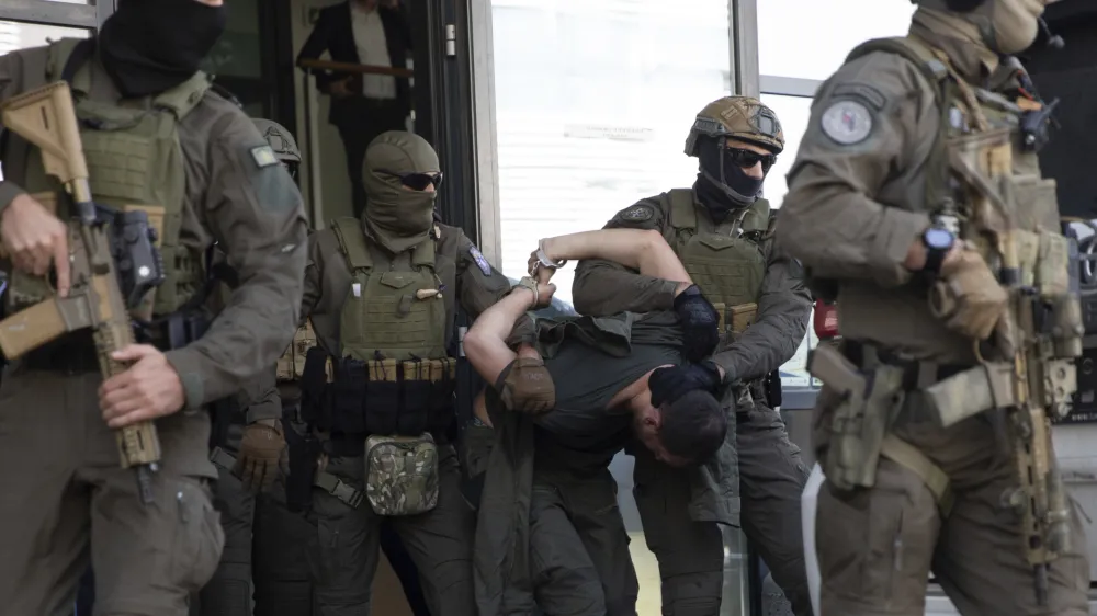 Kosovo police members of Special Intervention Unit escort one of the arrested Serb gunmen out of the court after the Kosovo shootout in capital Pristina, on Tuesday, Sept. 26, 2023. (AP Photo/Visar Kryeziu)