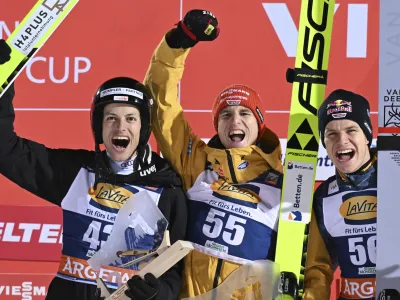 Winner Karl Geiger, center, from Germany celebrates on the podium next to second place, Gregor Deschwanden from Switzerland, left, and third place, Andreas Wellinger from Germany during the Nordic skiing/ski jumping World Cup, large hill men's second round in Klingenthal, Germany, Sunday, Dec. 10, 2023. (Hendrik Schmidt/dpa via AP)