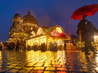 A person strolls past Christmas lights and decorations at the outdoor Christmas market at Humboldt Forum in front of Berlin Cathedral (Berliner Dom) in central Berlin, Germany, December 11, 2023. REUTERS/Lisi Niesner