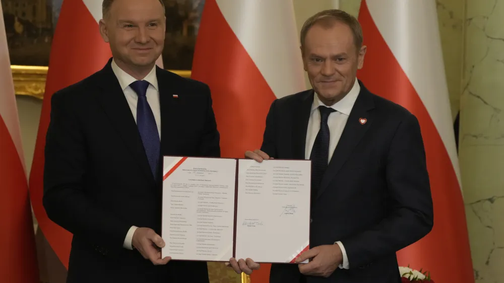 Poland's new Prime Minister Donald Tusk, right, and Poland's President Andrzej Duda pose for cameras during the swearing-in ceremony at the presidential palace in Warsaw, Poland, Wednesday, Dec. 13, 2023. Donald Tusk was sworn in by the president in a ceremony where each of his ministers was also taking the oath of office. (AP Photo/Czarek Sokolowski)