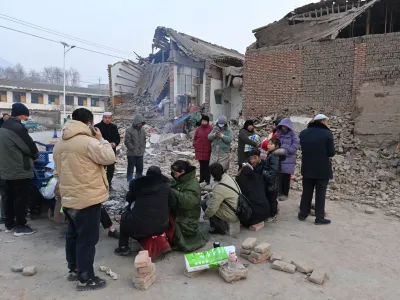 Residents keep warm by a fire next to damaged buildings at Dahejia town following the earthquake in Jishishan county, Gansu province, China December 19, 2023. cnsphoto via REUTERS  ATTENTION EDITORS - THIS IMAGE WAS PROVIDED BY A THIRD PARTY. CHINA OUT. NO COMMERCIAL OR EDITORIAL SALES IN CHINA