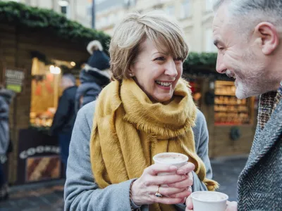 Mature couple are enjoying a cup of coffee as they explore the town christmas market.