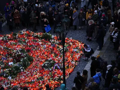 Mourners bring flowers and candles outside the building of Philosophical Faculty of Charles University in Prague, Czech Republic, Friday, Dec. 22, 2023. A lone gunman opened fire at a university on Thursday, killing more than a dozen people and injuring scores of people. (AP Photo/Petr David Josek)