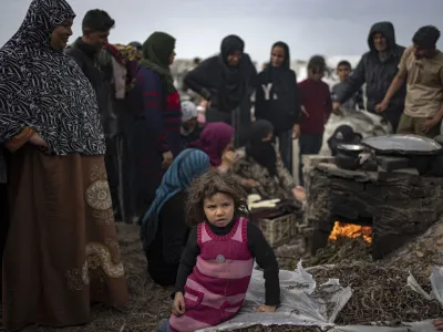 A little girl sits as Palestinians displaced by the Israeli bombardment wait for their turn to bake bread at the makeshift tent camp in the Muwasi area in Rafah, Gaza Strip, Saturday, Dec. 23, 2023. (AP Photo/Fatima Shbair)