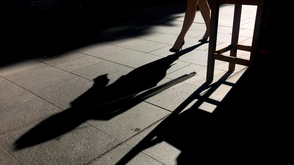 FILE PHOTO: A woman casts a shadow as she walks along a footpath past a coffee shop on a sunny, winter day in central Sydney, Australia July 25, 2017. REUTERS/David Gray/File Photo