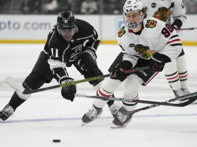 Los Angeles Kings center Anze Kopitar (11) and Chicago Blackhawks center Connor Bedard (98) reach for the puck during the third period of an NHL hockey game Thursday, April 18, 2024, in Los Angeles. (AP Photo/Ashley Landis)