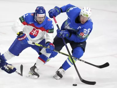 Jan Urbas of Slovenia, right, fights for a puck with Adam Janosik of Slovakia during the group B match between Slovenia and Slovakia at the ice hockey world championship in Riga, Latvia, Sunday, May 21, 2023. (AP Photo/Roman Koksarov)