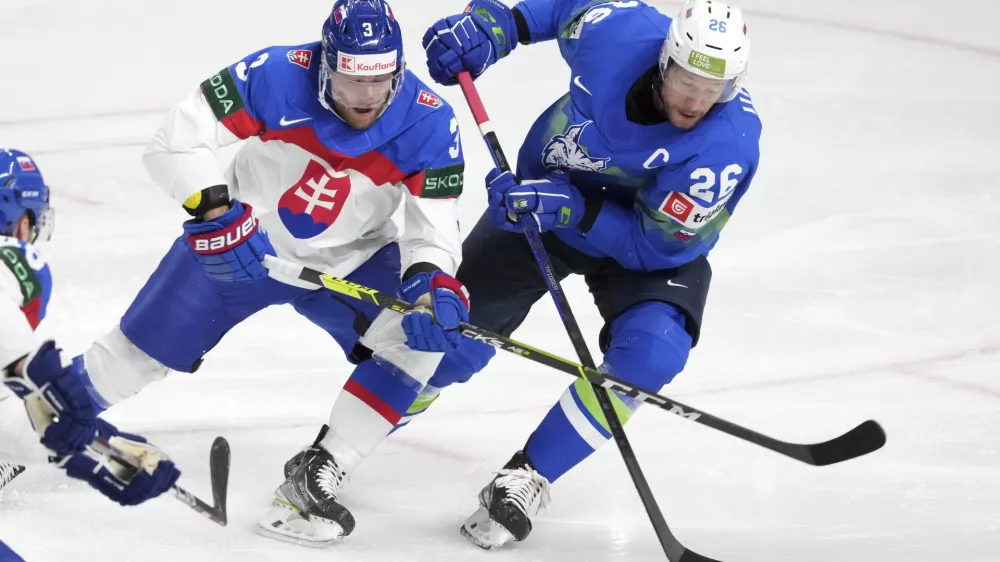 Jan Urbas of Slovenia, right, fights for a puck with Adam Janosik of Slovakia during the group B match between Slovenia and Slovakia at the ice hockey world championship in Riga, Latvia, Sunday, May 21, 2023. (AP Photo/Roman Koksarov)