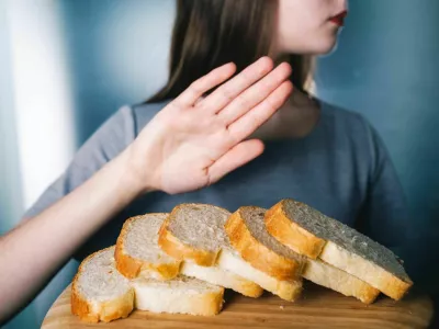 Gluten intolerance concept. Young girl refuses to eat white bread - shallow depth of field - selective focus on bread / Foto: Wojciech Kozielczyk