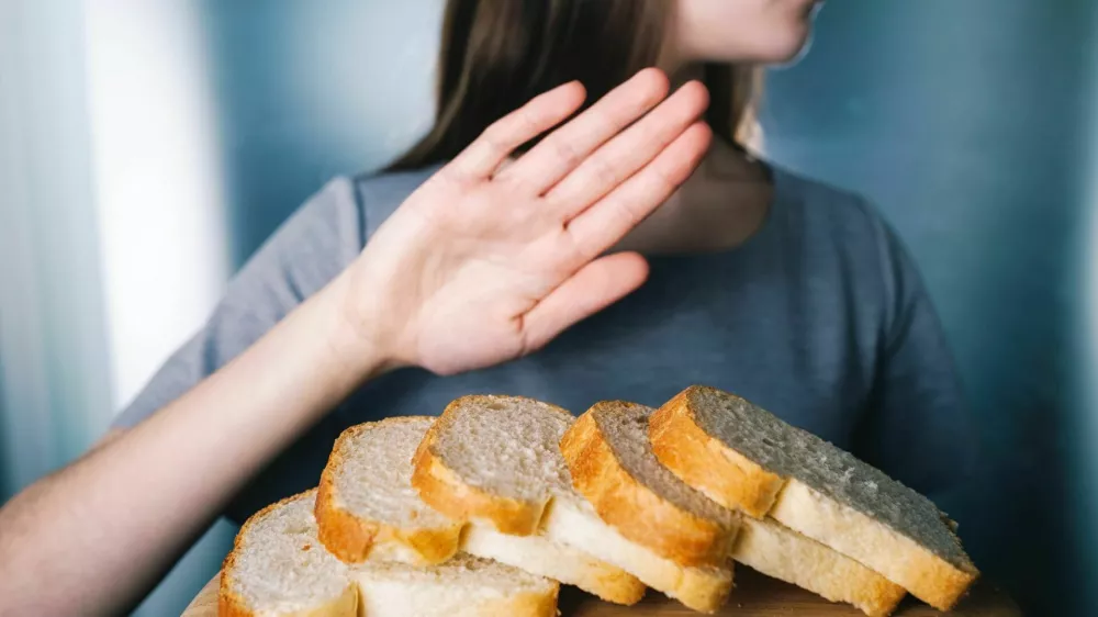 Gluten intolerance concept. Young girl refuses to eat white bread - shallow depth of field - selective focus on bread / Foto: Wojciech Kozielczyk