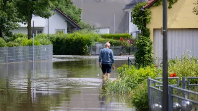 02 June 2024, Bavaria, Reichertshofen: A resident walks along a flooded street in the town center in Reichertshofen. Photo: Sven Hoppe/dpa