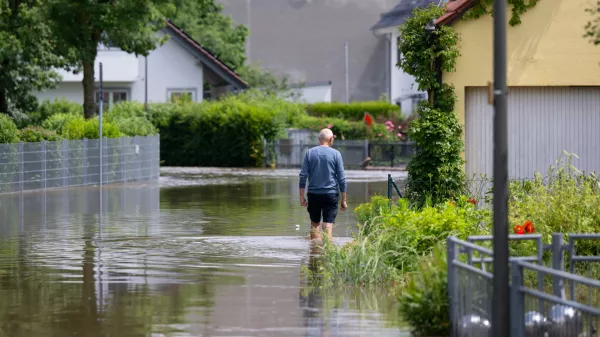 02 June 2024, Bavaria, Reichertshofen: A resident walks along a flooded street in the town center in Reichertshofen. Photo: Sven Hoppe/dpa