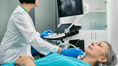 Ultrasound diagnostics of thyroid gland. Endocrinologist making ultrasonography to senior female patient at ultrasound office of medical clinic