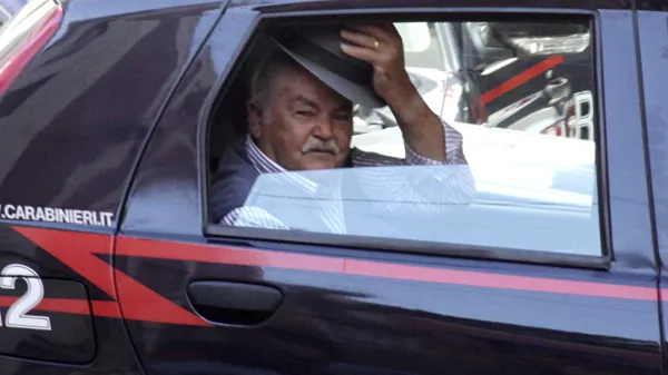 An unidentified man doffs his hat, as he rides in a Carabinieri (Paramilitary police) car after being arrested in Reggio Calabria, southern Italy, Tuesday, July 13, 2010, following one of the biggest operations ever against the powerful 'ndrangheta crime organization, in which 300 people were arrested including top bosses, and million of dollars (euros) in property seized. The pre-dawn raids Tuesday involved some 3,000 police across the country. Charges include murder, extortion, arms and drug trafficking and criminal association. Investigators described the operation as one of biggest blows ever to an organization that today is considered more powerful than the Sicilian Mafia. (AP Photo/Adriana Sapone)