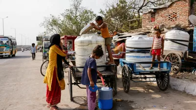 A girl fills water in a water cooler using a hose from a water tank attached to a three-wheeler cart on a hot summer day during a heatwave in New Delhi, India, June 3, 2024. REUTERS/Anushree Fadnavis