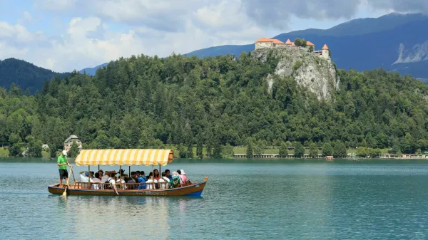 SLOVENIA, BLED - JULY 15, 2019: Traditional turist boat. Beautiful mountain lake in summer with castle on cliff and alps in the background.