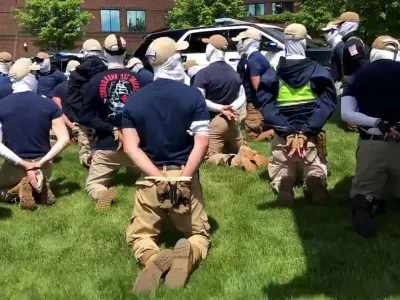 Police officers guard a group of men, who police say are among 31 arrested for conspiracy to riot and are affiliated with the white nationalist group Patriot Front, after they were found in the rear of a U Haul van in the vicinity of a North Idaho Pride Alliance LGBTQ+ event in Coeur d'Alene, Idaho, U.S. June 11, 2022 in this still image obtained from a social media video. North Country Off Grid/Youtube/via REUTERS THIS IMAGE HAS BEEN SUPPLIED BY A THIRD PARTY. MANDATORY CREDIT. NO RESALES. NO ARCHIVES.