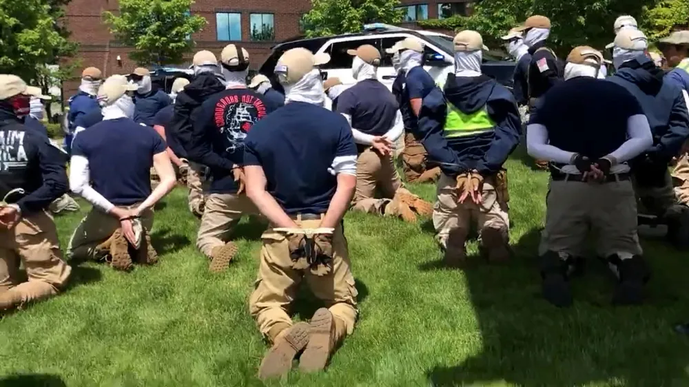 Police officers guard a group of men, who police say are among 31 arrested for conspiracy to riot and are affiliated with the white nationalist group Patriot Front, after they were found in the rear of a U Haul van in the vicinity of a North Idaho Pride Alliance LGBTQ+ event in Coeur d'Alene, Idaho, U.S. June 11, 2022 in this still image obtained from a social media video. North Country Off Grid/Youtube/via REUTERS THIS IMAGE HAS BEEN SUPPLIED BY A THIRD PARTY. MANDATORY CREDIT. NO RESALES. NO ARCHIVES.