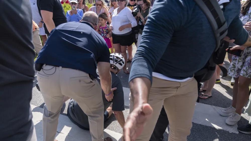 President Joe Biden is helped by U.S. Secret Service agents after he fell trying to get off his bike to greet a crowd on a trail at Gordons Pond in Rehoboth Beach, Del., Saturday, June 18, 2022. (AP Photo/Manuel Balce Ceneta)