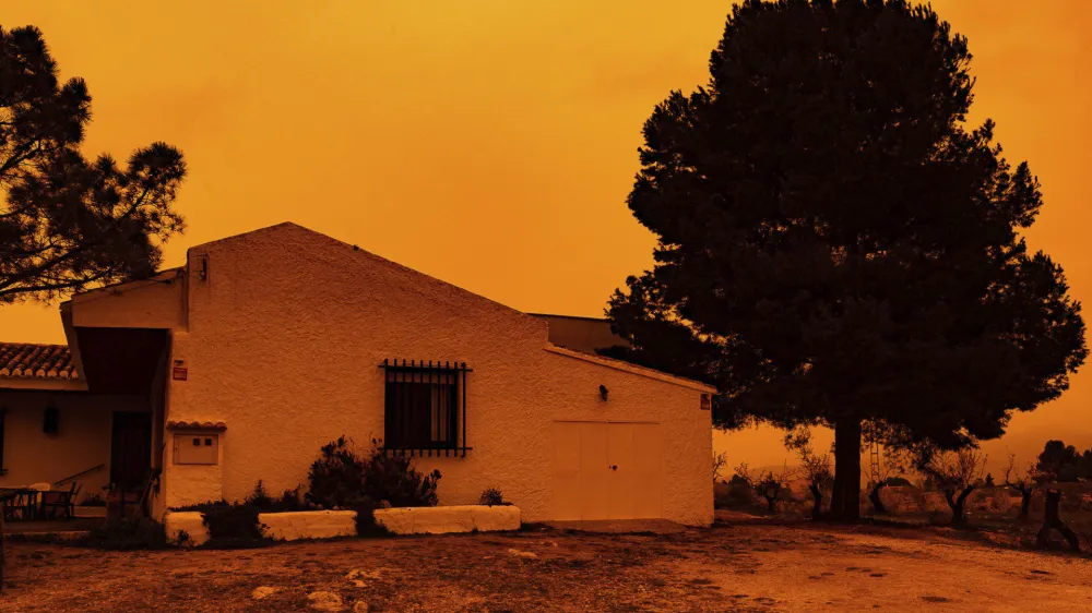 An orange sky is seen over a building in Navares, south eastern Spain, Monday March 14, 2022. Spain issued extremely poor air quality ratings for a large swathe of Spain Tuesday after a mass of hot air from the Sahara dumped loads of dust after crossing the Mediterranean. (Javier Carrion/Europa Press via AP)