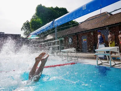 17 June 2022, United Kingdom, London: A person jumps into the pool for an early morning cool down at London Fields Lido, in Hackney, east London. Photo: Jonathan Brady/PA Wire/dpa