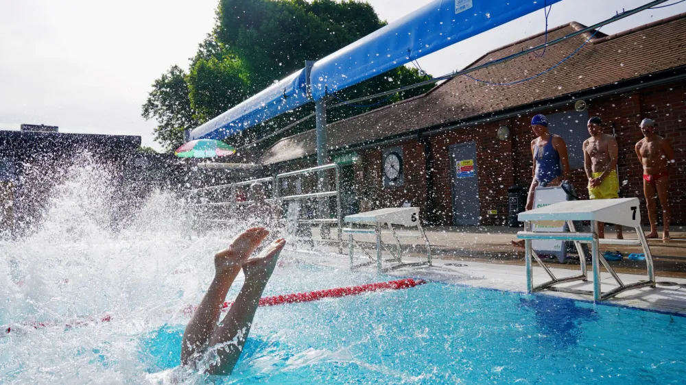 17 June 2022, United Kingdom, London: A person jumps into the pool for an early morning cool down at London Fields Lido, in Hackney, east London. Photo: Jonathan Brady/PA Wire/dpa