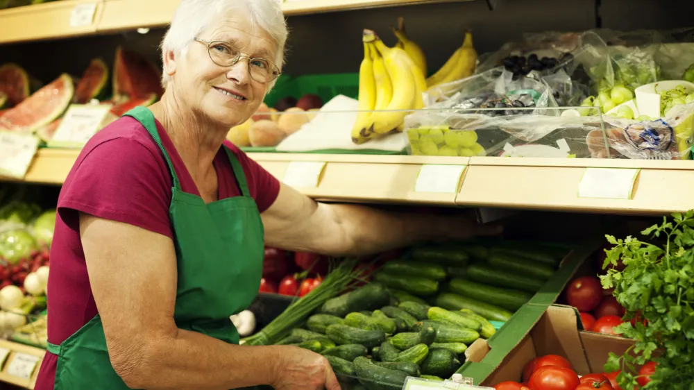 Senior woman arranging vegetables on shelf