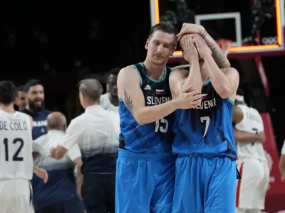 Slovenia's Klemen Prepelic (7) is consoled by teammate Slovenia's Gregor Hrovat (15) after their loss to France in a men's basketball semifinal round game at the 2020 Summer Olympics, Thursday, Aug. 5, 2021, in Saitama, Japan. (AP Photo/Eric Gay)