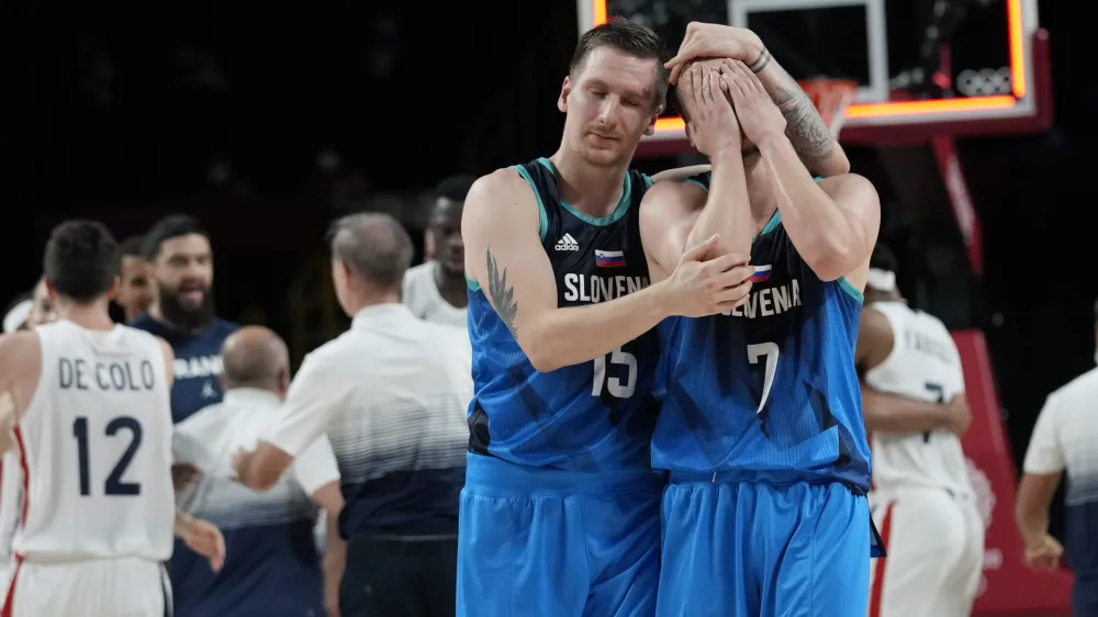 Slovenia's Klemen Prepelic (7) is consoled by teammate Slovenia's Gregor Hrovat (15) after their loss to France in a men's basketball semifinal round game at the 2020 Summer Olympics, Thursday, Aug. 5, 2021, in Saitama, Japan. (AP Photo/Eric Gay)