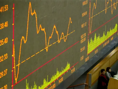 FILE PHOTO: Chinese floor traders monitor their computers below a graph at Shanghai Stock Exchange March 22, 2004./File Photo