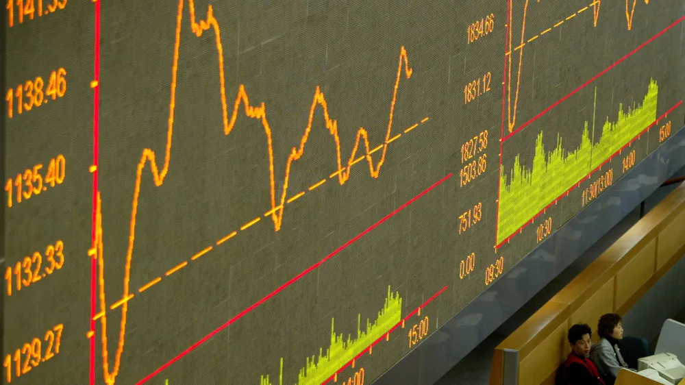 FILE PHOTO: Chinese floor traders monitor their computers below a graph at Shanghai Stock Exchange March 22, 2004./File Photo