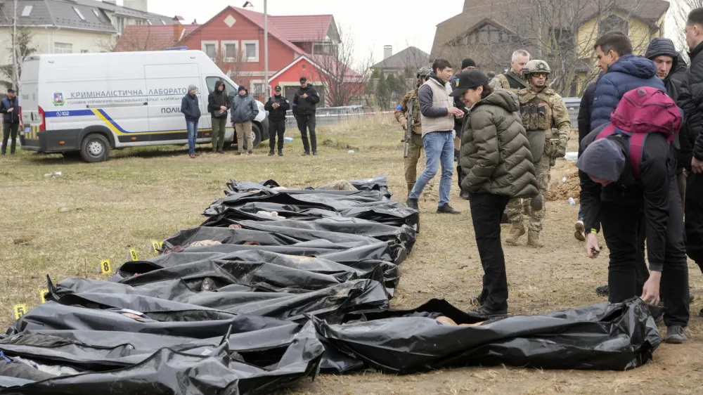 Ukrainian Prosecutor General Iryna Venediktova, center, looks at the exhumed bodies of civilians killed during the Russian occupation in Bucha, on the outskirts of Kyiv, Ukraine, Friday, April 8, 2022. An international organization formed to identify the dead and missing from the 1990s Balkan conflicts is preparing to send a team of forensics experts to Ukraine as the death toll mounts more than six weeks into the war caused by Russia's invasion. (AP Photo/Efrem Lukatsky)