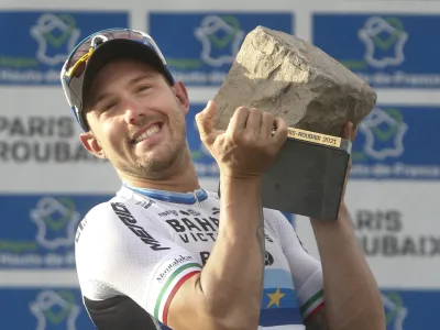 Sonny Colbrelli of Italy lifts the cobblestone trophy after winning the men's Paris Roubaix, a 258 kilometer (160.3 miles) one-day-race cycling race, at the velodrome in Roubaix, northern France, Sunday, Oct. 3, 2021. (AP Photo/Michel Spingler)