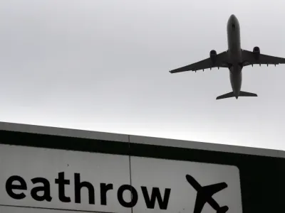 A plane takes off over a road sign near Heathrow Airport in London, Tuesday, June 5, 2018. The British Cabinet has approved the construction of a third runway at Heathrow Airport, and to put the long-running issue up for a parliamentary vote. (AP Photo/Kirsty Wigglesworth)