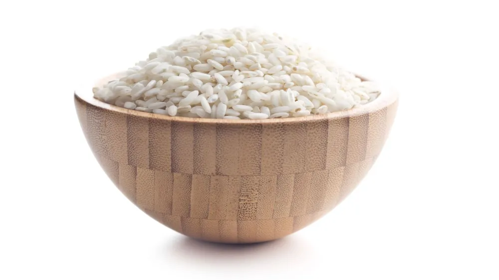 The arborio rice in wooden bowl. Isolated on white background.