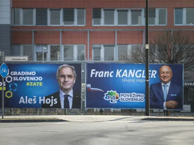 Notranji minister Aleš Hojs in državni sekretar Franc Kangler sta pred ministrstvom, generalno policijsko upravo in Nacionalnim preiskovalnim uradom, kjer ima politika v času tretje Janševe vlade izrazit vpliv, dala postaviti svoja plakata.