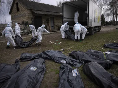 FILE - Volunteers load bodies of civilians killed in Bucha onto a truck to be taken to a morgue for investigation, in Bucha on the outskirts of Kyiv, Ukraine, Tuesday, April 12, 2022. (AP Photo/Rodrigo Abd, File)
