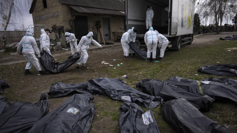 FILE - Volunteers load bodies of civilians killed in Bucha onto a truck to be taken to a morgue for investigation, in Bucha on the outskirts of Kyiv, Ukraine, Tuesday, April 12, 2022. (AP Photo/Rodrigo Abd, File)