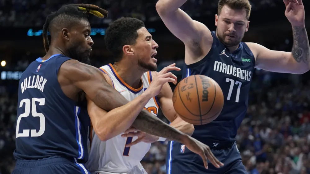 Phoenix Suns guard Devin Booker (1) is fueled by Dallas Mavericks forward Reggie Bullock (25) as guard Luka Doncic (77) looks on during the first half of Game 6 of an NBA basketball second-round playoff series, Thursday, May 12, 2022, in Dallas. (AP Photo/Tony Gutierrez)