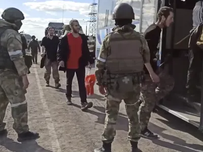 In this photo taken from video released by the Russian Defense Ministry Press Service on Tuesday, May 17, 2022, Russian servicemen watch Ukrainian servicemen boarding a bus as they are being evacuated from the besieged Azovstal steel plant in Mariupol, Ukraine. More than 260 fighters, some severely wounded, were pulled from a steel plant on Monday that is the last redoubt of Ukrainian fighters in the city and transported to two towns controlled by separatists, officials on both sides said. (Russian Defense Ministry Press Service via AP)