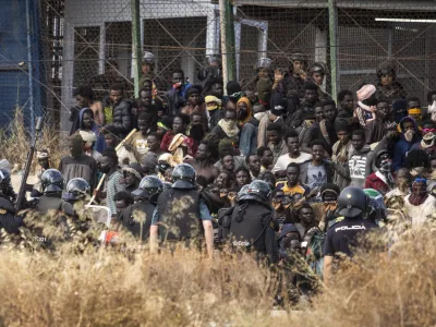 Riot police officers cordon off the area after migrants arrive on Spanish soil and crossing the fences separating the Spanish enclave of Melilla from Morocco in Melilla, Spain, Friday, June 24, 2022. Dozens of migrants stormed the border crossing between Morocco and the Spanish enclave city of Melilla on Friday in what is the first such incursion since Spain and Morocco mended diplomatic relations last month. (AP Photo/Javier Bernardo)
