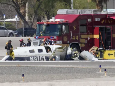 Officials investigate the wreckage of a plane at the site of a fatal crash at the North Las Vegas Airport, Sunday, July 17, 2022, in North Las Vegas, Nev. Authorities say several people are dead after two small planes collided at North Las Vegas Airport. (AP Photo/John Locher)