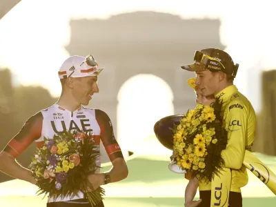 Cycling - Tour de France - Stage 21 - Paris La Defense Arena to Champs-Elysees - France - July 24, 2022 Jumbo - Visma's Jonas Vingegaard celebrates on the podium wearing the overall leader's yellow jersey after winning the Tour de France with second placed UAE Team Emirates' Tadej Pogacar REUTERS/Christian Hartmann