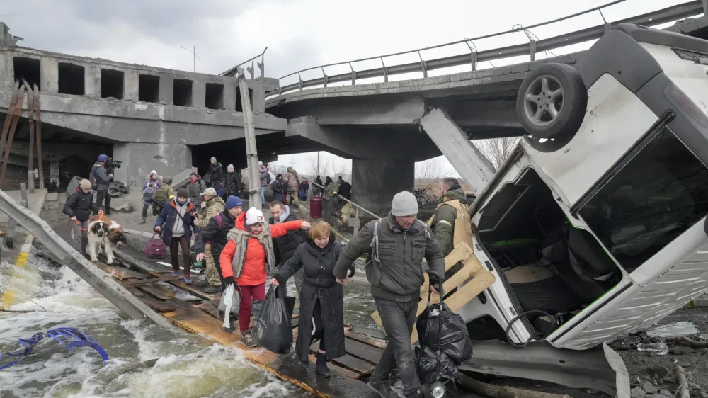 People cross an improvised path under a destroyed bridge while fleeing the town of Irpin close to Kyiv, Ukraine, Monday, March 7, 2022.Russia announced yet another cease-fire and a handful of humanitarian corridors to allow civilians to flee Ukraine. Previous such measures have fallen apart and Moscow's armed forces continued to pummel some Ukrainian cities with rockets Monday. (AP Photo/Efrem Lukatsky)